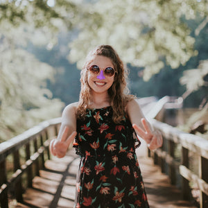 Blonde woman in black dress giving peace sign on bridge